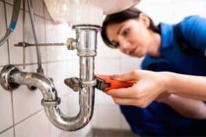 A plumber addresses a pipe issue in a home that may need more extensive services, including repiping.